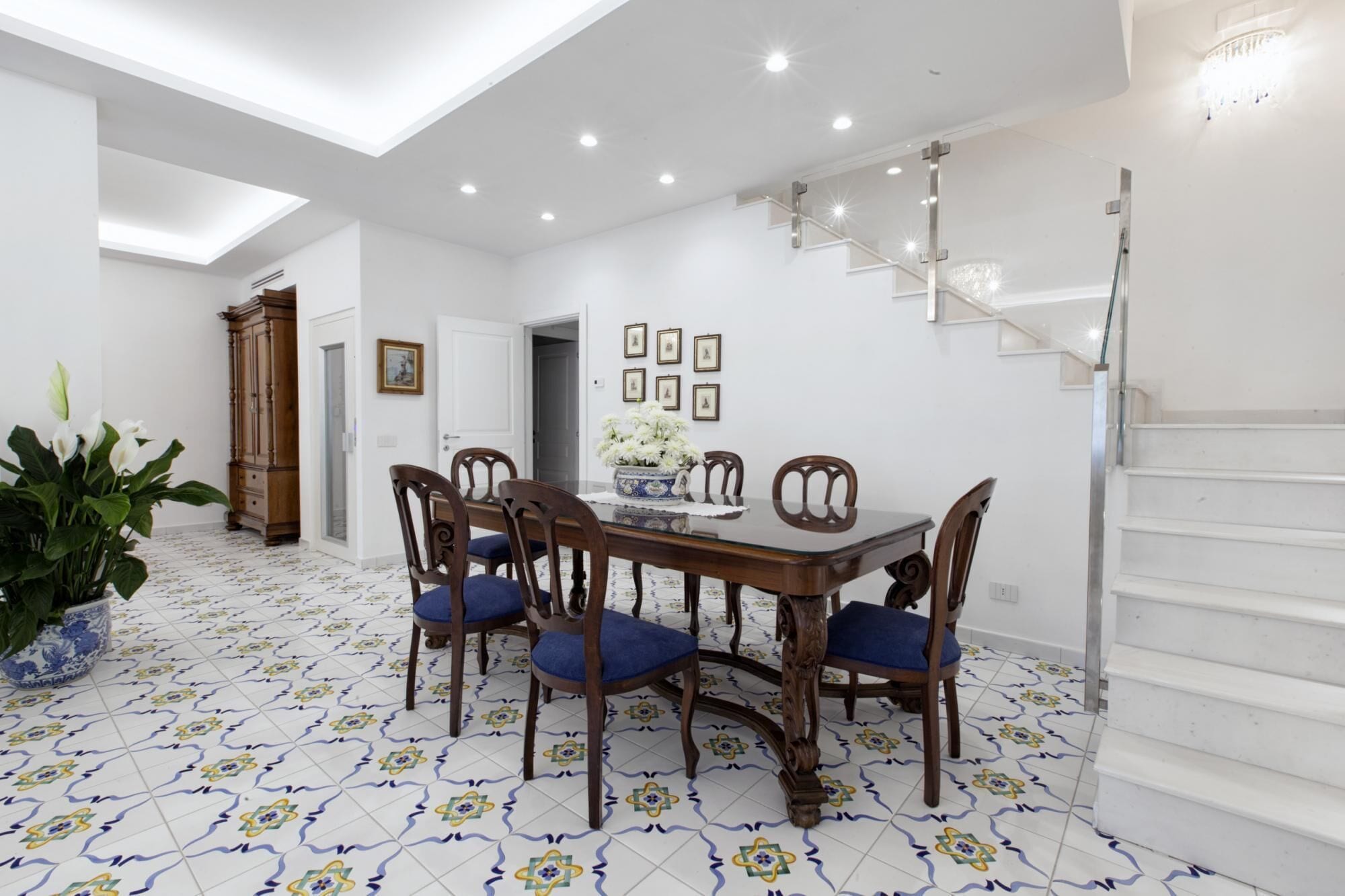 Un coin repas avec une table et des chaises en bois, un vase rempli de fleurs et un escalier.