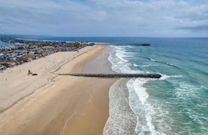 A beach with a pier extending into the ocean, a sandy shore, and a coastal town in the background. - Newly Updated! - Oceanview Sea Gem Cottage- Bikes/ Boards,10 sec walk to beach (Newport Beach)