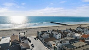 Un pueblo costero con edificios cerca de la playa, un muelle que se adentra en el mar y un cielo despejado.