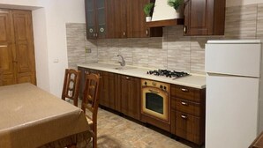 A kitchen with wooden cabinets, a gas stove, a built-in oven, and a refrigerator. - Residence the garden on the Nera river - apt2 (Borgo Cerreto)