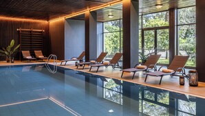 A modern indoor swimming pool with lounge chairs and large windows. - Hotel Meandro - Lake View (Gargnano)