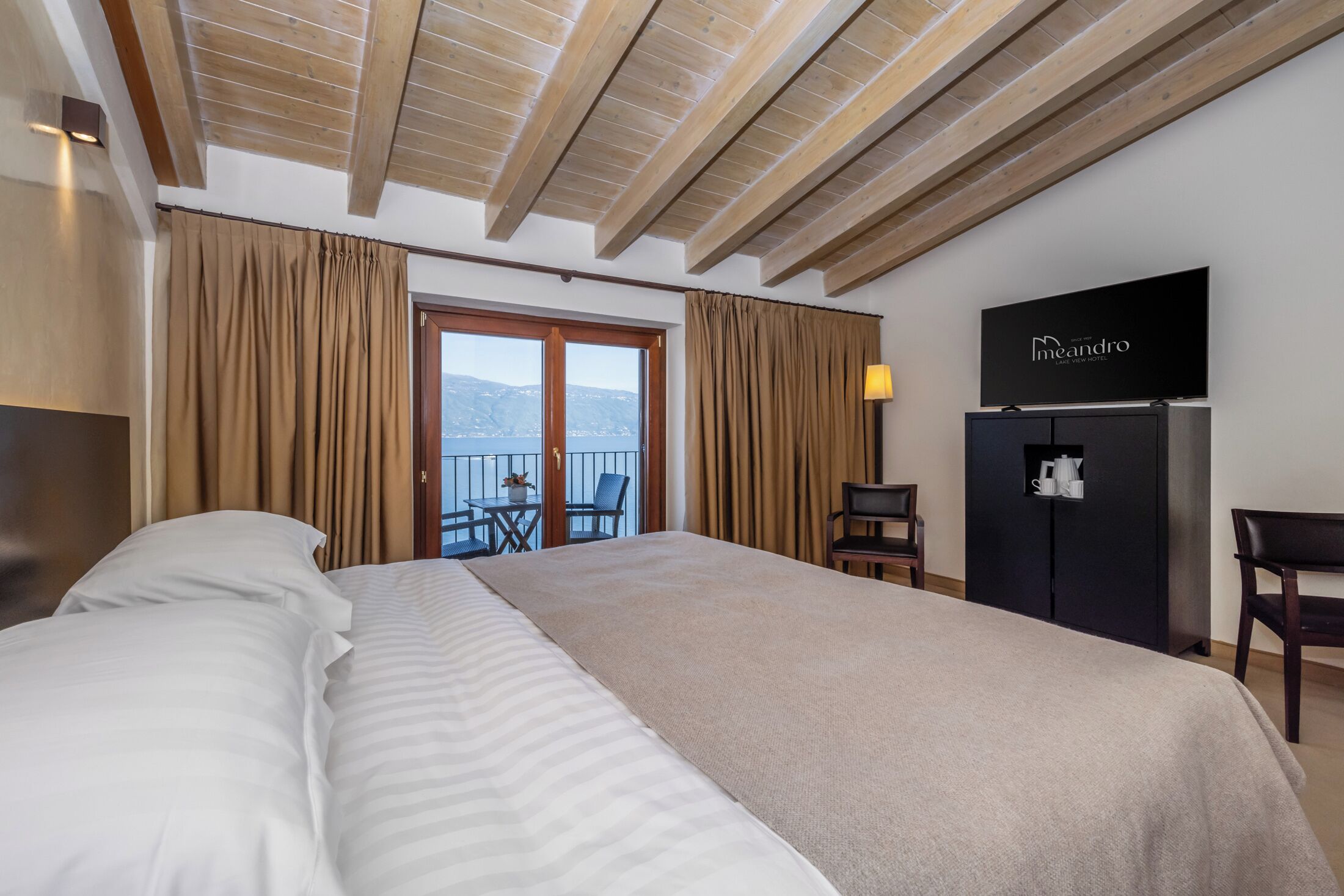 Een hotelkamer met een groot bed, een kledingkast, een bureau, een stoel en een balkon met uitzicht.