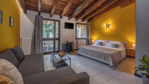 A bedroom with a bed, a sofa, a small table, and a window. - Hotel Meandro - Lake View (Gargnano)