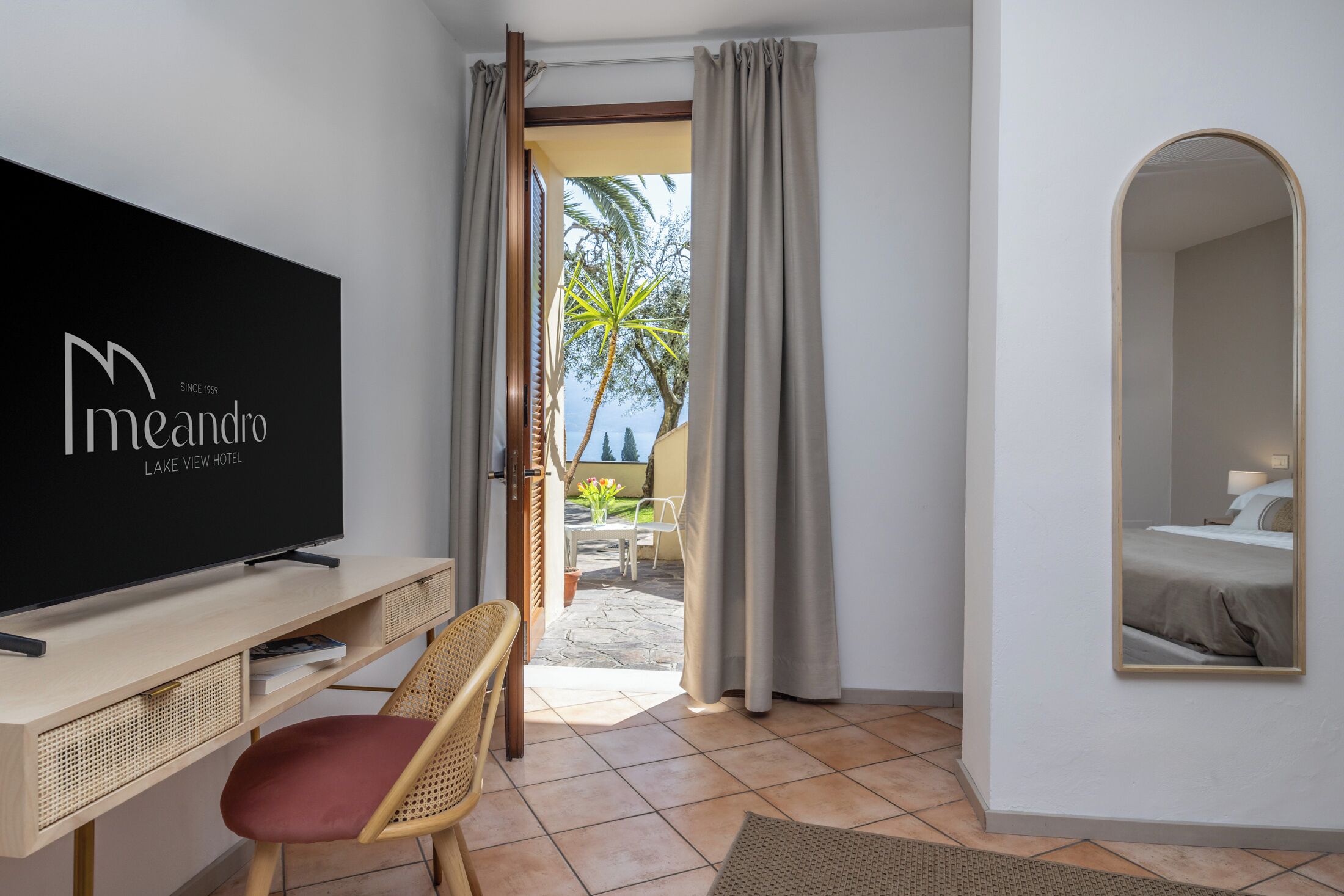 Habitación de hotel con televisión, escritorio, silla, cama y vistas al exterior.