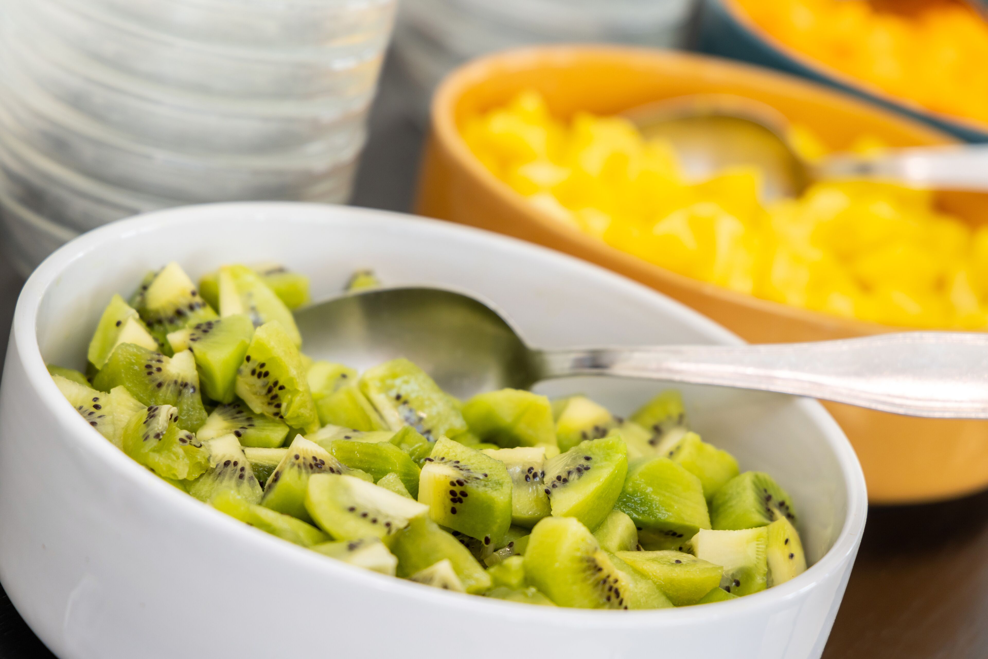 A bowl of sliced kiwi fruit with a spoon.