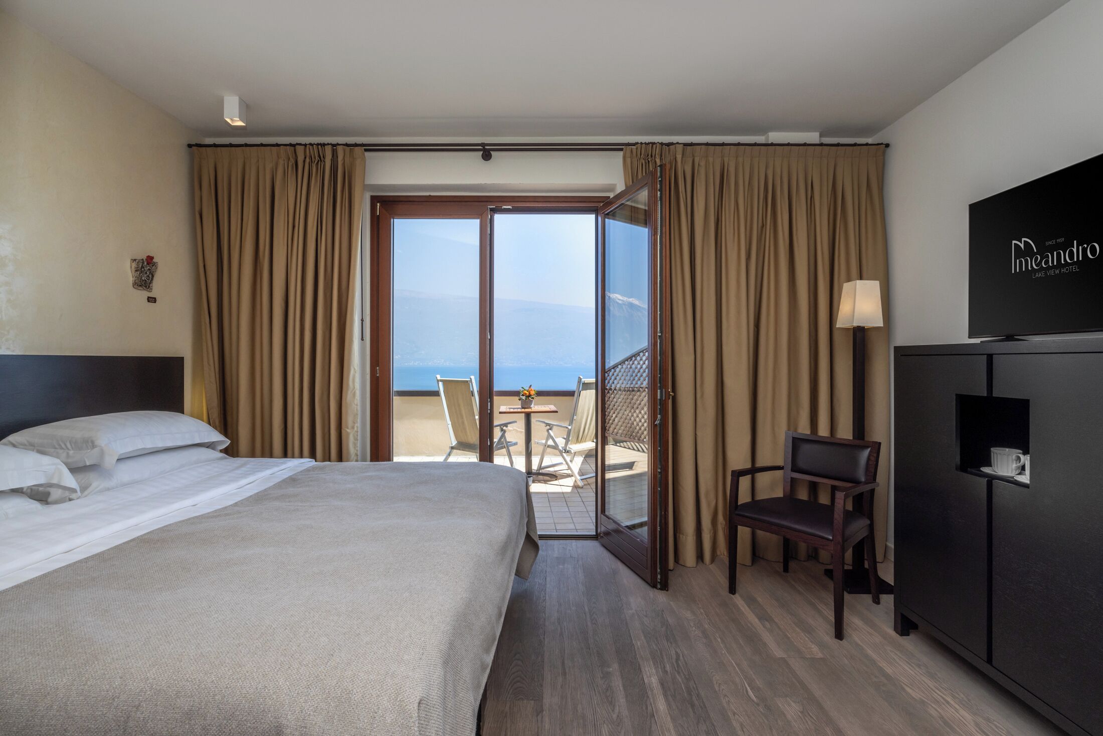 Habitación de hotel con cama, escritorio, silla, televisión y vista al mar.