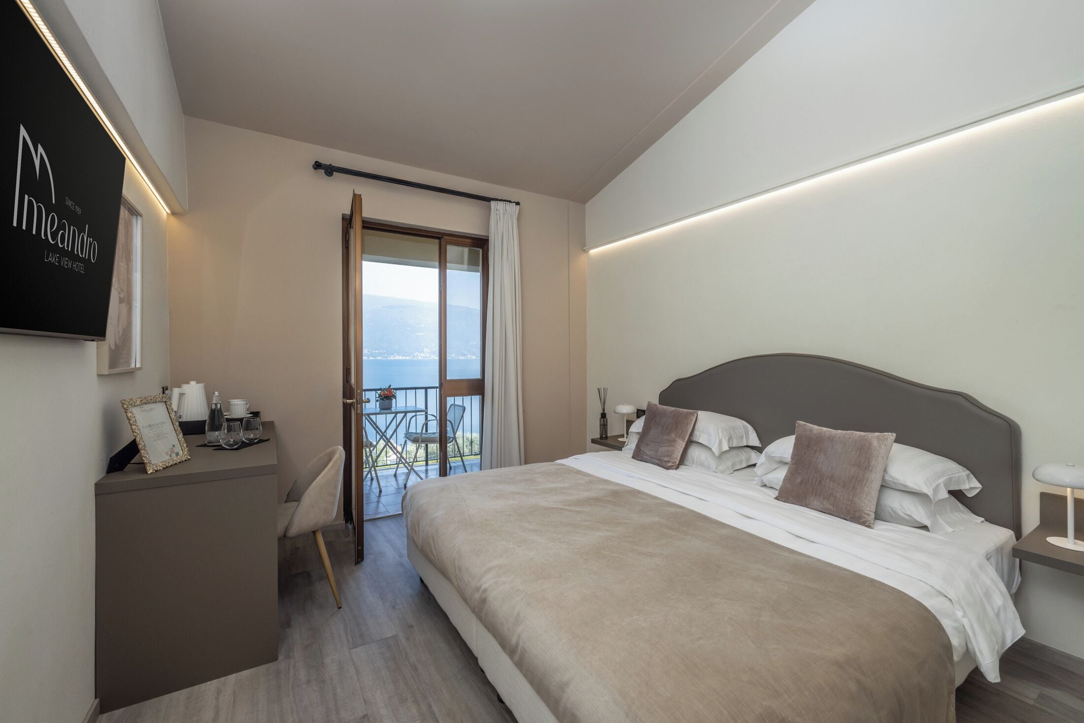 Une chambre d’hôtel moderne dotée d’un grand lit, d’un bureau avec une chaise et d’un balcon offrant une vue agréable.