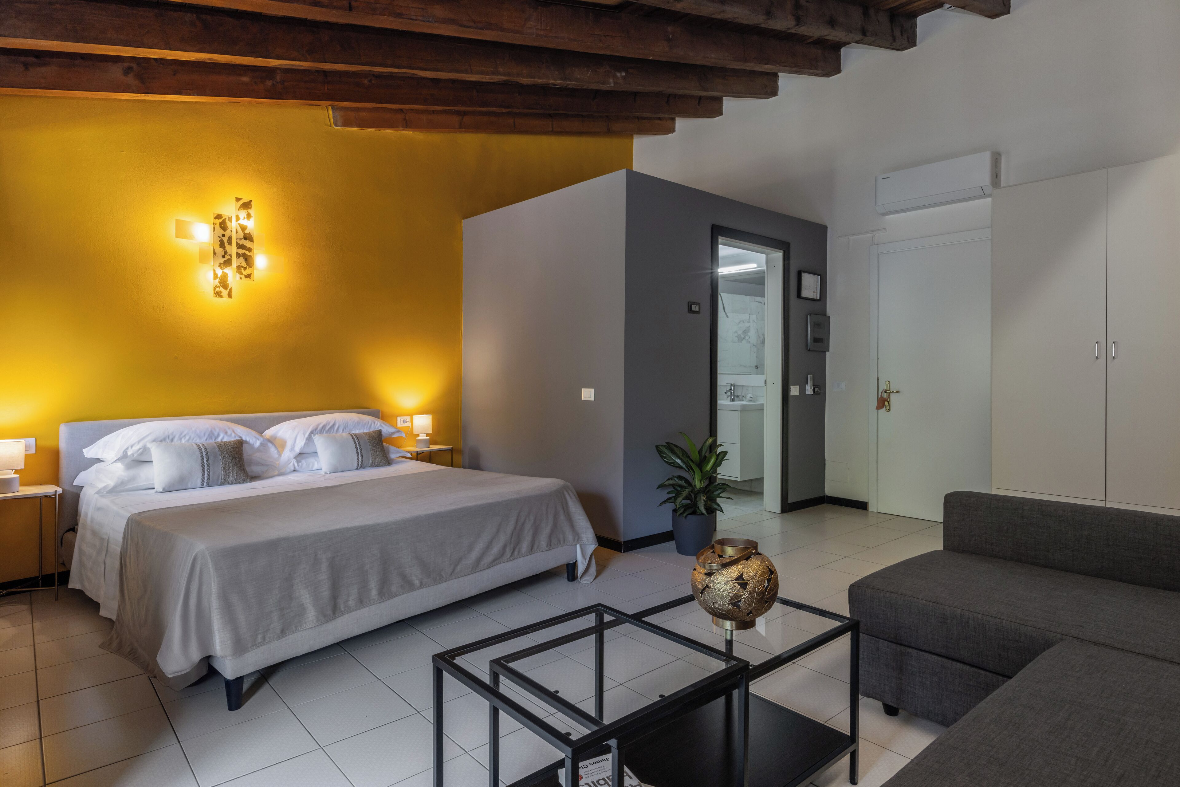 A bedroom with a bed, bedside tables, a nightstand, a potted plant, and a decorative globe.