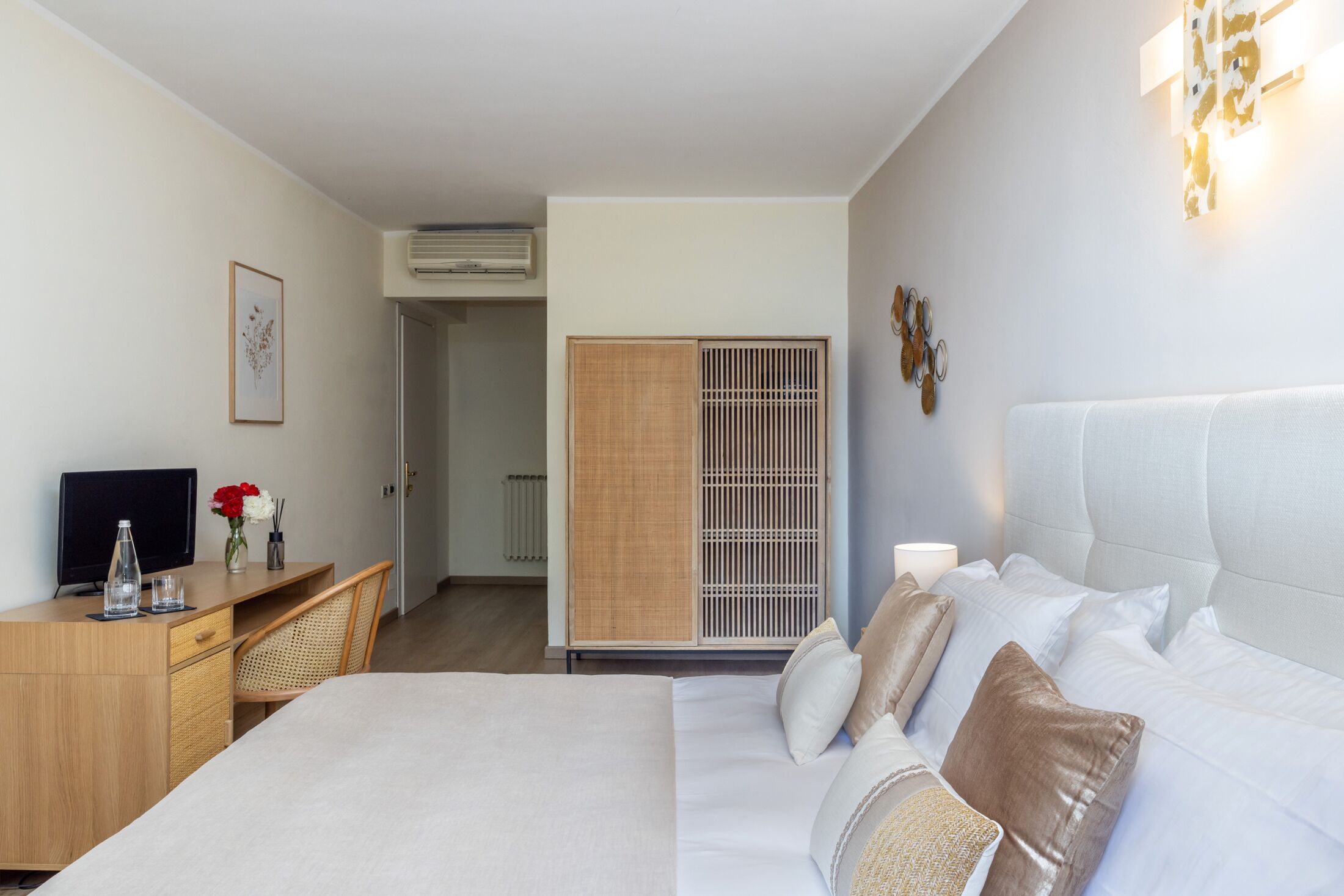 A hotel room with a bed, a desk, a television, and a wardrobe.