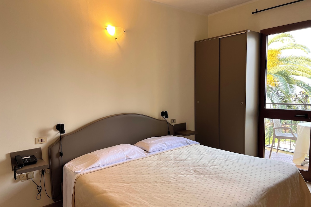 Un dormitorio con cama, mesita de noche, lámpara y armario.