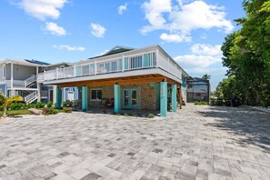 A two-story building with a covered patio area, a stone facade, and a balcony. - Go to the beach from expansive heated pool home (Fort Myers Beach)
