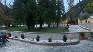 An outdoor patio area with stone flooring, a curved stone wall, and small potted plants. - Apartment with terrace and garden  (Borgo Cerreto)