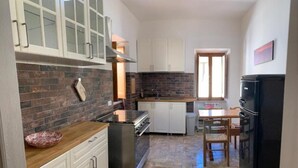 A compact kitchen with white cabinets, a brick backsplash, a gas stove, and a black refrigerator. - Apartment with terrace and garden  (Borgo Cerreto)