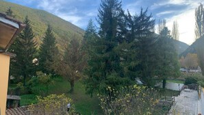 A residential area with a house, a large tree, and a hill in the background. - Apartment with terrace and garden  (Borgo Cerreto)