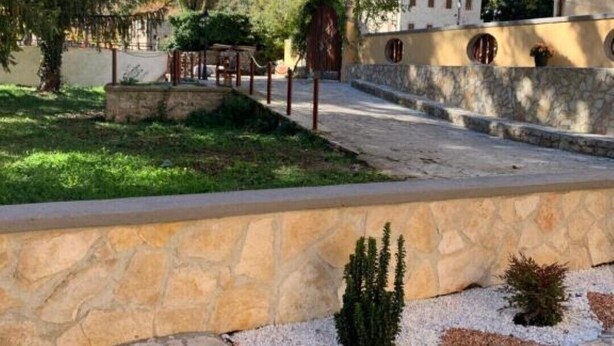 A courtyard with stone walls, a small garden, and a building with a stone facade. - Apartment with terrace and garden  (Borgo Cerreto)