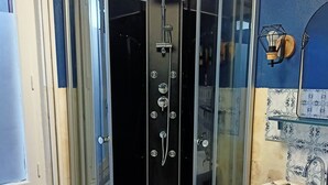 Ein Badezimmer mit Duschkabine, Waschbecken und einem kleinen Mülleimer.