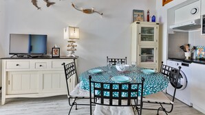 Un comedor con una mesa redonda, sillas y un televisor sobre un mueble.