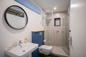 A bathroom with a sink, mirror, toilet, and glass shower enclosure. - Forty On L by CTHA (Cape Town)