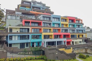 Een meerlaags gebouw met een modern architectonisch ontwerp, voorzien van balkons en grote ramen.