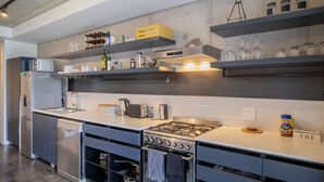 Een moderne keuken met een ingebouwde vaatwasser, roestvrijstalen apparatuur en open planken voor extra opbergruimte.