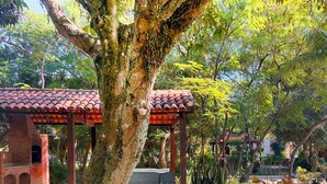 A covered outdoor area with a tiled roof, benches, and a brick structure in the background. - Local 102 Apartment  (Rio de Janeiro)