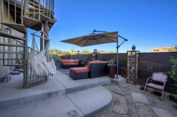 Relax in style on this outdoor patio with comfortable seating, a large umbrella, and a beautiful garden view.