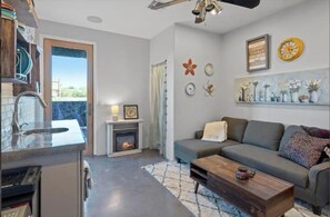 Relax by the fireplace in this cozy living space, featuring a sofa, coffee table, and kitchen area.
