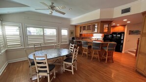 A spacious kitchen with wooden cabinets, a black refrigerator, and a dining area with a round table and chairs. - Florida Beachfront Bliss just steps from the Sand (St. Pete Beach)