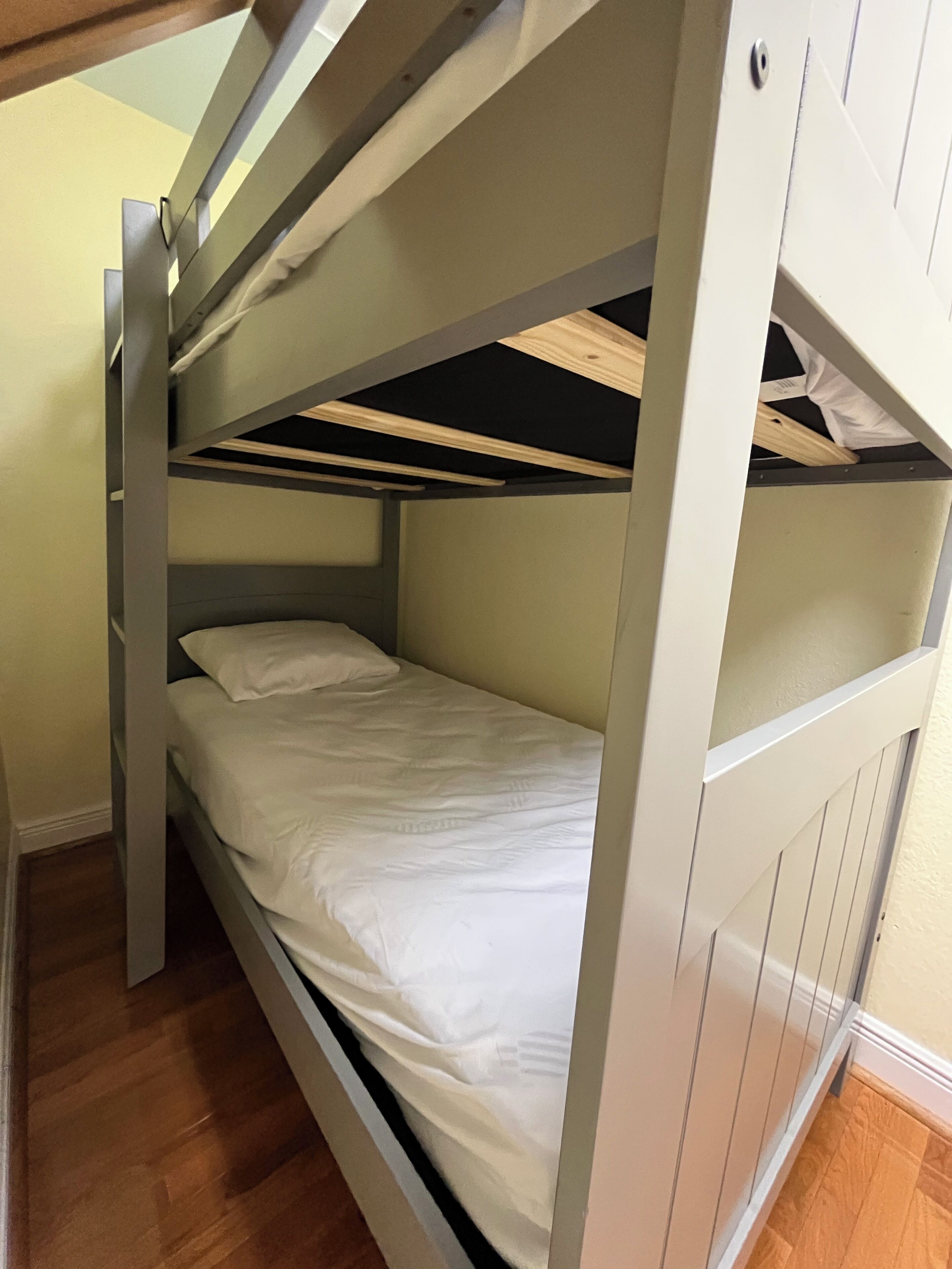 Una cama litera con estructura de madera y ropa de cama blanca.