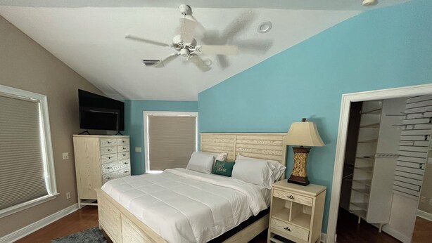 A bedroom with a bed, nightstands, a ceiling fan, a dresser, a TV, and a closet. - Florida Beachfront Bliss just steps from the Sand (St. Pete Beach)