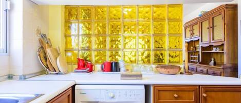 A kitchen with a washing machine, wooden cabinets, a sink, and a yellow-tiled backsplash.