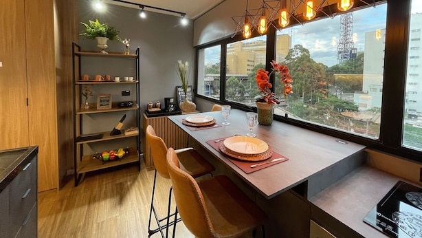 Un comedor moderno con una mesa de madera, sillas y vistas de la ciudad a través de amplios ventanales.