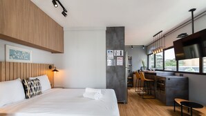 Una habitación de hotel moderna con una cama grande, una pequeña cocina y un área de descanso.