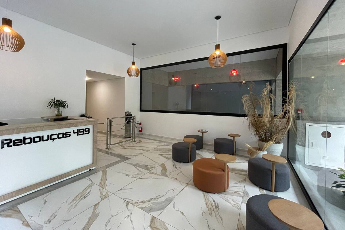 Un espace d’accueil moderne doté d’un sol en marbre, d’un comptoir de réception et de sièges comprenant des tables rondes et des poufs.