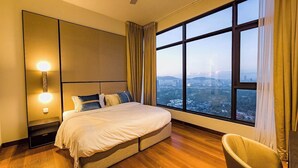 Een moderne hotelkamer met een groot bed, uitzicht op de stad, een plafondventilator en een stoel.