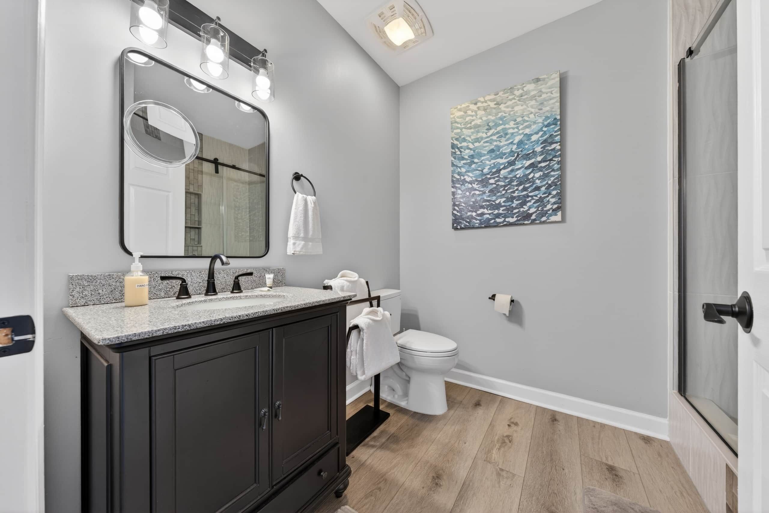 A bathroom with a vanity, sink, mirror, and toilet.