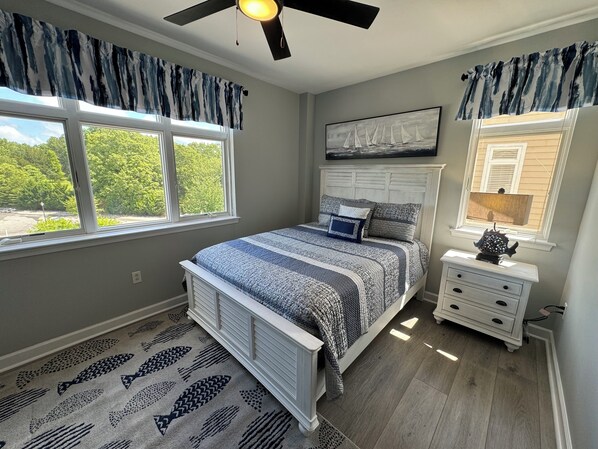 A bedroom with a bed, a nightstand, a ceiling fan, and a window with curtains. - #2400 Pointe - Studio Suite at Mariners SML (Huddleston)
