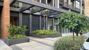 Een modern gebouw met een overdekte ingang, een terras en een boom.