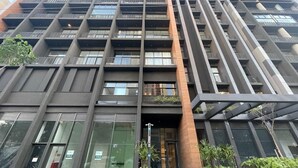 Een modern meerlaags gebouw met een gegrid façade, grote ramen en balkons.