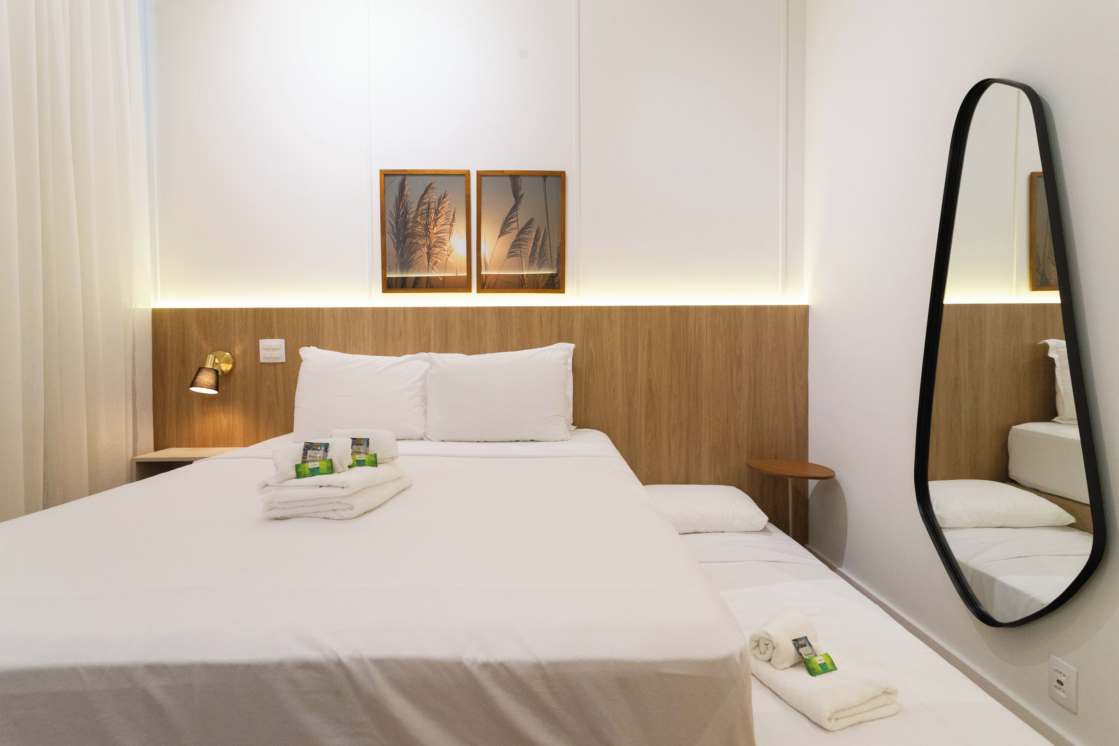 Un dormitorio de hotel con una cama grande, dos mesitas de noche, un espejo y obras de arte en la pared.