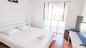 Quarto com cama, escrivaninha e janela.
