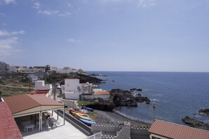 A coastal town with buildings, a rocky shoreline, and boats. - Las Eras Nest Hostel (Arico)