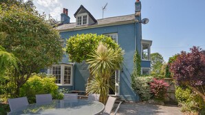 Ein blaues Haus mit einer Terrasse, einem runden Glastisch und Stühlen.