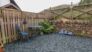 Eine Terrasse mit einer Steinmauer, einem Holzzaun und einem Tisch mit Stühlen.