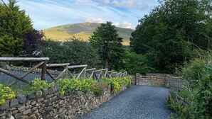 A stone pathway leading to a wooden gate, surrounded by greenery and a stone wall. - Beech Croft (Keswick)
