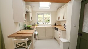A compact kitchen with white cabinetry, a wooden countertop, and a skylight. - Beech Croft (Keswick)