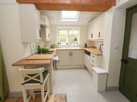 A compact kitchen with white cabinetry, a wooden countertop, and a skylight.