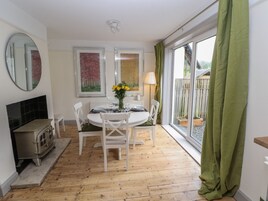 A dining area with a round table set for four, white chairs, a small stove, and artwork on the walls.