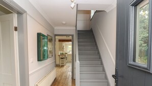 A hallway with a wooden floor, a grey staircase, and a window on the right. - Beech Croft (Keswick)