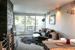 Relax by the fireplace in a cozy seating area with a sofa and coffee table, and step out to the patio with outdoor furniture.